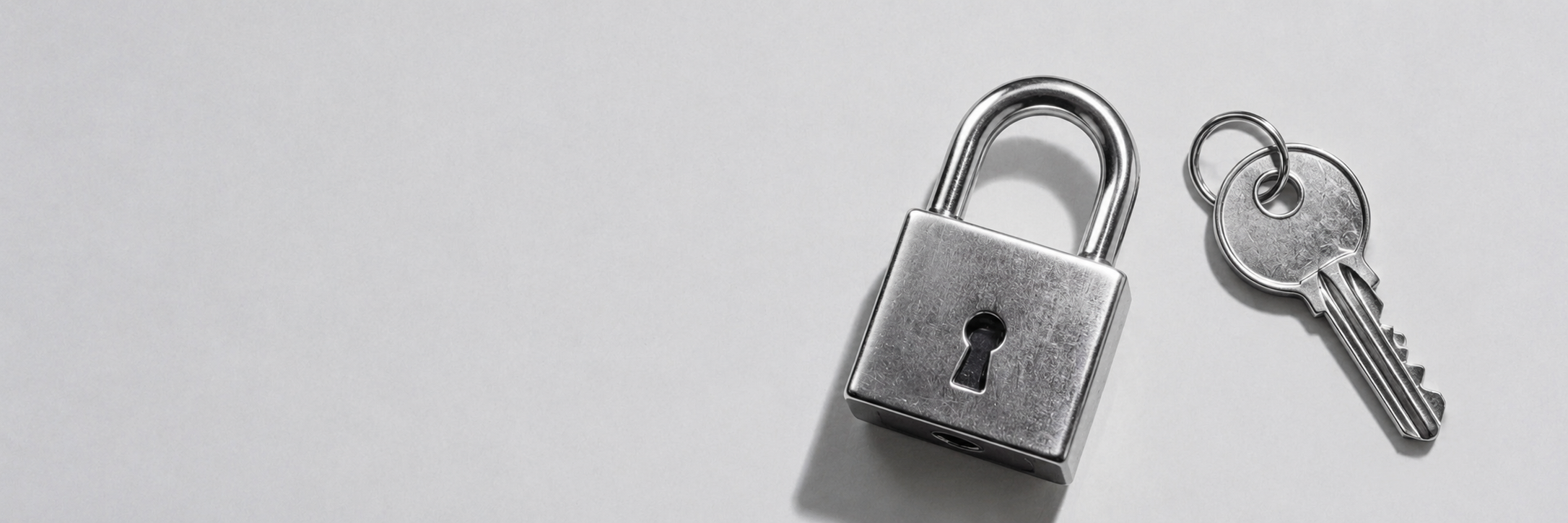 A polished silver padlock and key resting on a soft surface